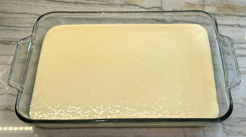 Pour the creamy layer on top of the cake mixture and spread it evenly. 