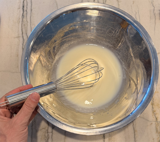Sprinkle in 1/3 of the white chocolate pudding mix and whisk together. Let stand 1 minute. Then sprinkle in 1/3 more of the pudding mix and whisk together. Let stand another minute. Then sprinkle in the remaining pudding mix and whisk together until combined. 