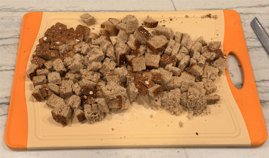 Cut bread into 1/2-inch squares and place in a large mixing bowl. 