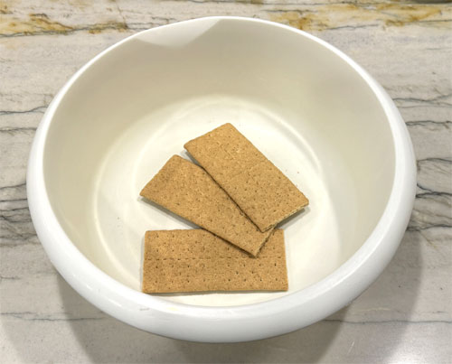 Crush the graham crackers, then pour the melted butter over top and mix it together. 