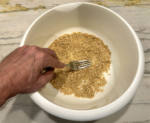 Crush the graham crackers, then pour the melted butter over top and mix it together. 
