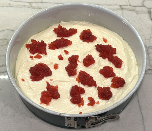Put the jelly in a bowl and smash it with a fork until it breaks apart. Then, drop pieces of the jelly over the cheesecake. 