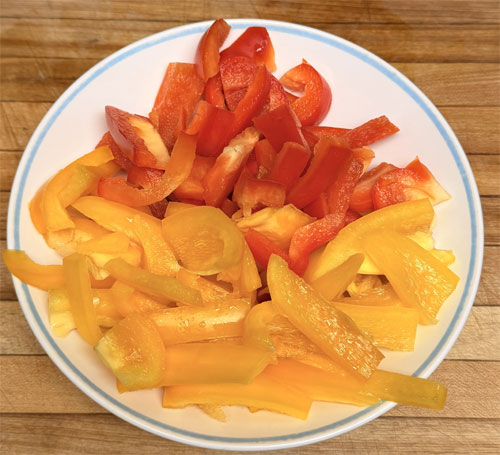 Spread chopped onions and bell peppers over chicken.