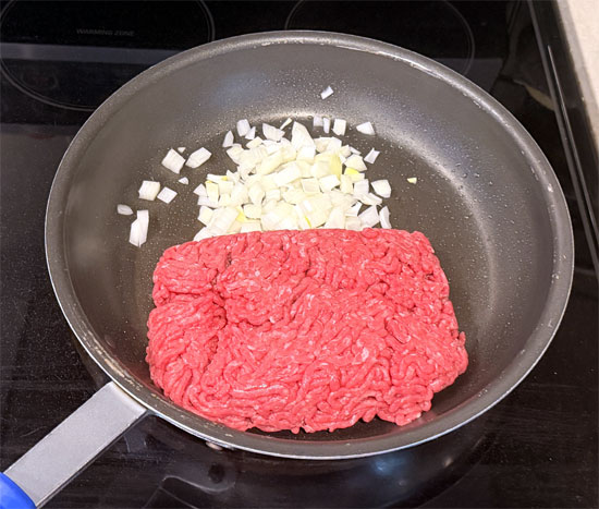 Heat a large skillet over medium heat and lightly coat with olive oil spray. Add the beef and onion. Break up the beef and cook until it's no longer pink.