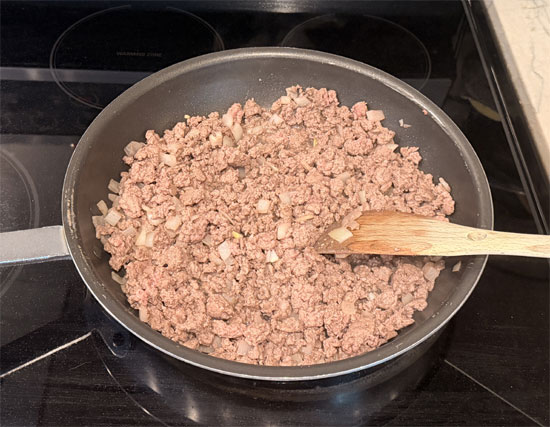 Heat a large skillet over medium heat and lightly coat with olive oil spray. Add the beef and onion. Break up the beef and cook until it's no longer pink.