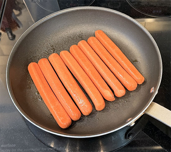 Heat a frying pan over medium heat and add the hot dogs, rolling them every minute or so for 5 to 7 minutes, until they're browned on all sides and heated through.