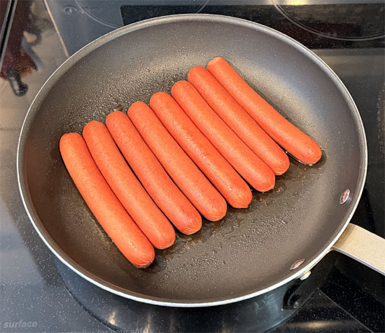 Heat a frying pan over medium heat and add the hot dogs, rolling them every minute or so for 5 to 7 minutes, until they're browned on all sides and heated through.