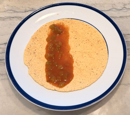 Lay out the tortillas and spread 2 Tbsp. of the enchilada mixture on each one. Wrap each tortilla around a hot dog and place it seam side down in the baking dish, on top of the beans.