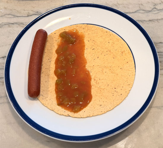 Lay out the tortillas and spread 2 Tbsp. of the enchilada mixture on each one. Wrap each tortilla around a hot dog and place it seam side down in the baking dish, on top of the beans.