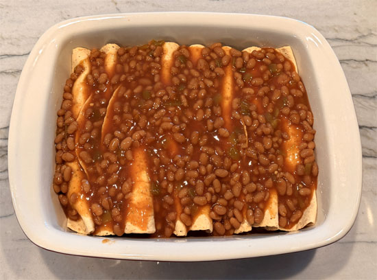 Mix the remaining baked beans with the remaining enchilada mixture and spread it over the rolled hot dogs.