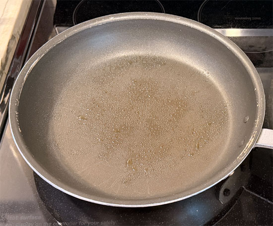 While the casserole bakes, cut the onion and bell peppers into slices. Then heat the olive oil in a lidded pan over medium heat. Sauté the onion and bell peppers for about 6 minutes.