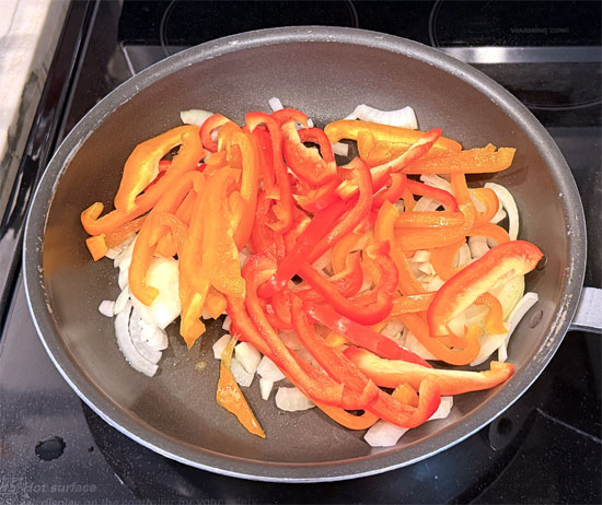 While the casserole bakes, cut the onion and bell peppers into slices. Then heat the olive oil in a lidded pan over medium heat. Sauté the onion and bell peppers for about 6 minutes.