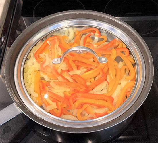 While the casserole bakes, cut the onion and bell peppers into slices. Then heat the olive oil in a lidded pan over medium heat. Sauté the onion and bell peppers for about 6 minutes.