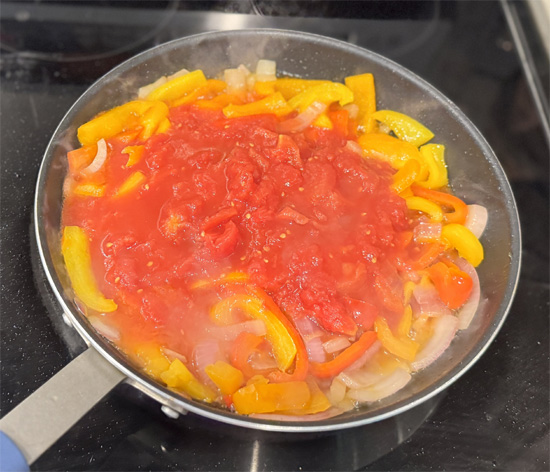 Add tomatoes: Add plum tomatoes to the pan, crushing lightly with a spoon until broken apart.