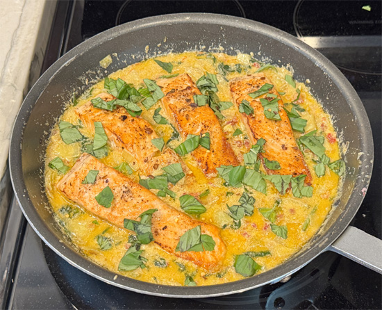 Return salmon to the pan and spoon sauce over the top. Sprinkle with basil and optional red pepper flakes.