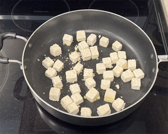 Heat a large skillet over medium-high heat. Add the olive oil and then the tofu cubes. Cook until one side is golden brown and crisp, about 3 minutes. Flip and cook on the other side for three more minutes until the tofu is golden brown and crisp. Transfer the cooked tofu to a plate.