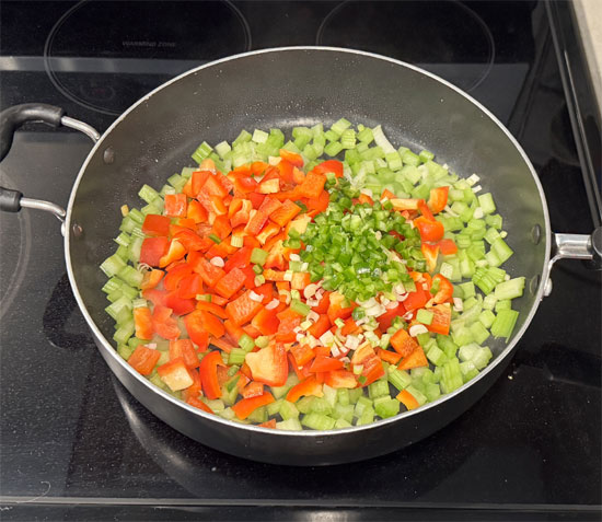 Keep the pan on medium-high and add the red bell pepper, celery, scallions and jalapeno. Cook, stirring constantly, until the red pepper starts to soften and the vegetables char, about 4 minutes.