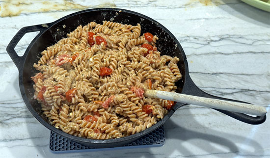 Remove the tomato-feta mixture from the oven and stir in the drained pasta until well coated.