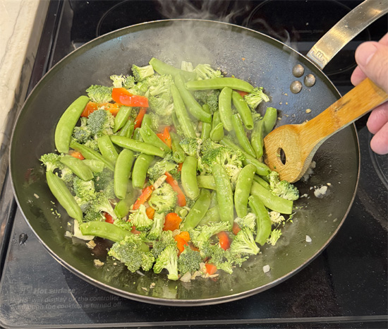 Pour in half of the stir fry sauce. Add the sugar snap peas and broccoli. Stir and cook for 1 minute.
