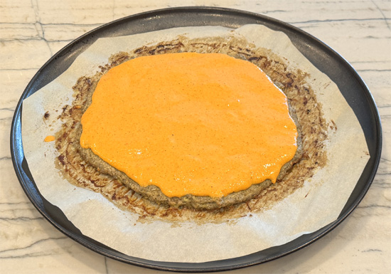 Add sauce: Spread the chilled red pepper sauce evenly over the meat crust, right to the edge. Save any extra sauce for dipping. 