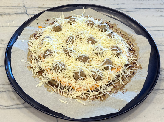 Sprinkle cheese: Sprinkle shredded mozzarella over sauce and meatballs. I spread it right over the edge a little.