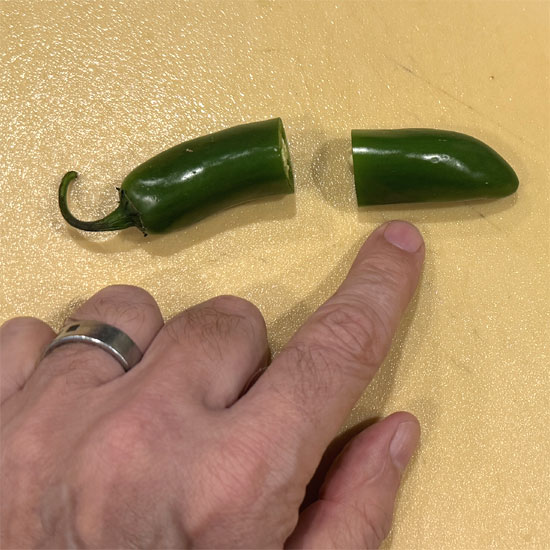 Cut a serrano pepper in half, remove the seeds, and mince them into small pieces.