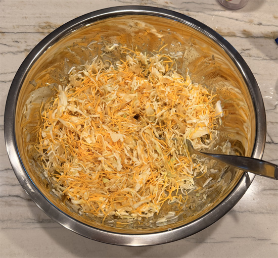 In a large bowl, combine the sauerkraut, coleslaw, vinegar, sweeteners, mustard, both cheeses, and remaining 1 Tbsp Everything Bagel seasoning. Mix well.