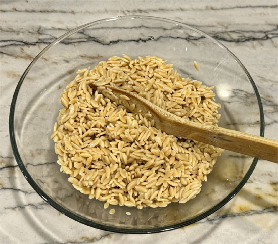 Once orzo is cooked, drain and transfer to a large bowl.