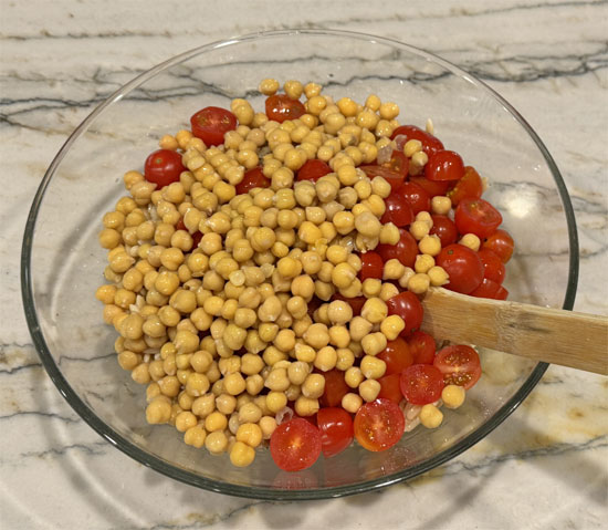 Pour half the dressing over the hot orzo. Add chickpeas, tomatoes, and olives. Toss well.
