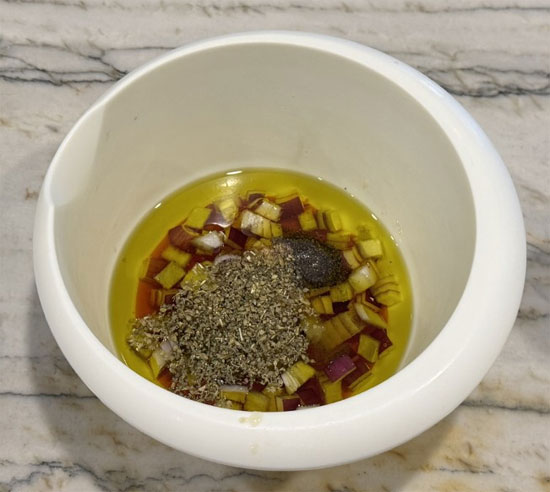While the orzo cooks, make the dressing. In a medium bowl, whisk together olive oil, red wine vinegar, red onion, garlic, oregano, 1/2 teaspoon salt, and 1/2 teaspoon pepper until smooth.