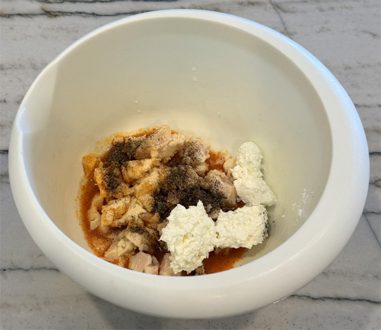 Drain chicken and place in a bowl. Add buffalo sauce, garlic powder, pepper and cream cheese. Mix well with a fork.