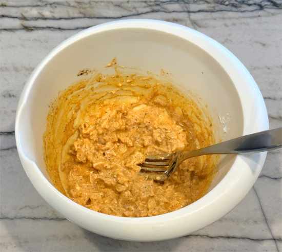 Drain chicken and place in a bowl. Add buffalo sauce, garlic powder, pepper and cream cheese. Mix well with a fork.