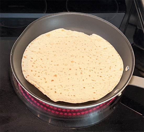Warm a pan over medium heat, then lightly toast the tortilla for 15 to 20 seconds per side, just until it's soft and pliable.