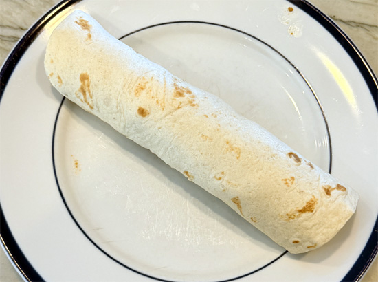 Roll the tortilla up tightly and cut in half.