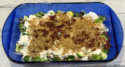 Once the Brussels sprouts are removed from the oven, top them with the Greek yogurt mixture, panko breadcrumbs, and chopped bacon. Stir everything together. 