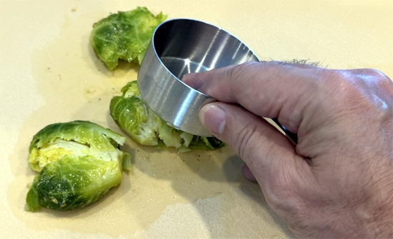 Lay a piece of parchment paper on a baking sheet. Then, put the Brussels sprouts on the sheet and smash them gently but firmly. 