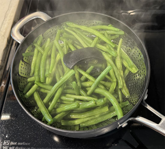 Once the water is boiling, place the steamer basket in the pot, add the green beans, and cover with a lid. Steam for about 15 minutes, or until the beans are tender.