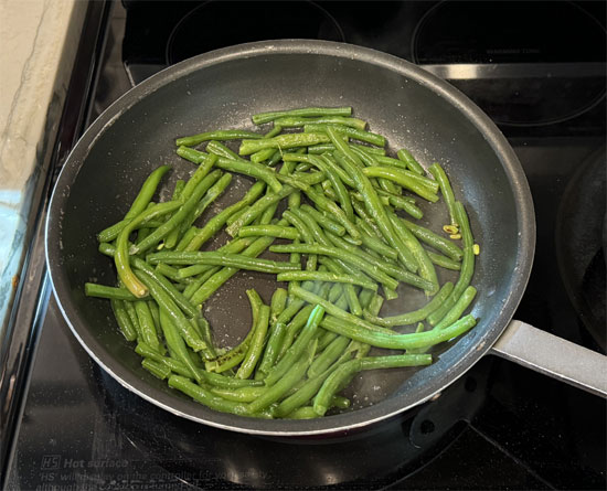 Add the steamed green beans to the skillet, season with salt and pepper, and sauté for 3-5 minutes, using tongs or a spatula to turn them. When they start to brown slightly, they’re ready to serve.