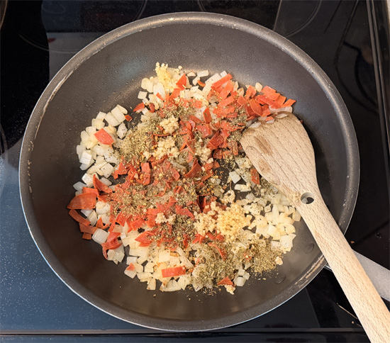 Add the garlic, half of the pepperoni slices chopped, Italian seasoning and red pepper flakes. Stir constantly for 1 minute. 