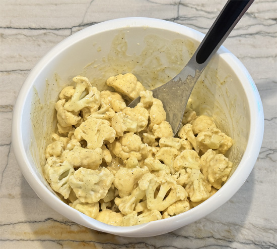 Whisk the beer into the batter. Then dip the cauliflower into the batter and then into the breadcrumb mixture. Place the pieces on the greased baking sheet. Then lightly drizzle the olive oil over top of the cauliflower.
