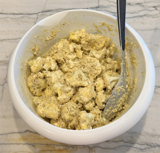 Whisk the beer into the batter. Then dip the cauliflower into the batter and then into the breadcrumb mixture. Place the pieces on the greased baking sheet. Then lightly drizzle the olive oil over top of the cauliflower.