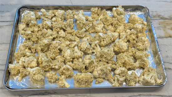 Whisk the beer into the batter. Then dip the cauliflower into the batter and then into the breadcrumb mixture. Place the pieces on the greased baking sheet. Then lightly drizzle the olive oil over top of the cauliflower.