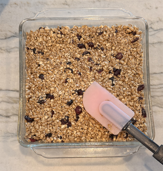 Pour the syrup over the oat mixture and stir until everything is thoroughly coated, then press it firmly and evenly into the prepared pan.