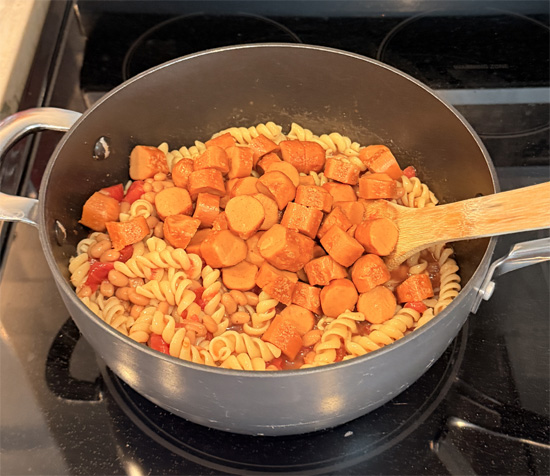 Stir in the pasta and hot dog pieces. Keep heating and stirring until everything is hot all the way through. Divide into 4 servings for a meal or 8 servings for a side dish.