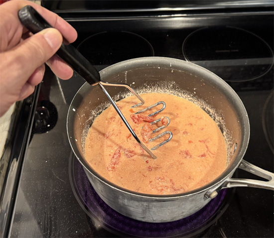Add the tomatoes and their juices. Use a potato masher to crush them. Then stir in the drained lentils and salt.