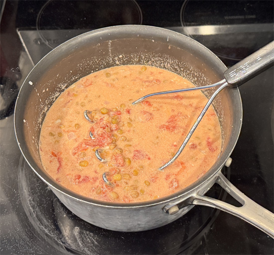 Add the tomatoes and their juices. Use a potato masher to crush them. Then stir in the drained lentils and salt.